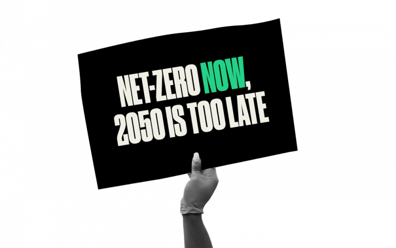 Hand holding sign reading 'Net-zero now. 2050 is too late.'